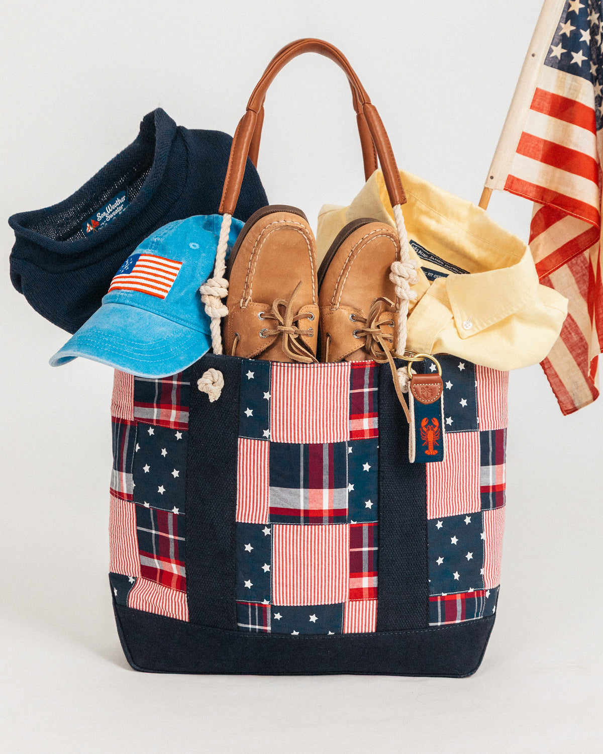 Patchwork tote bag with American flag design, containing shoes, hats, and a flag on a white background.